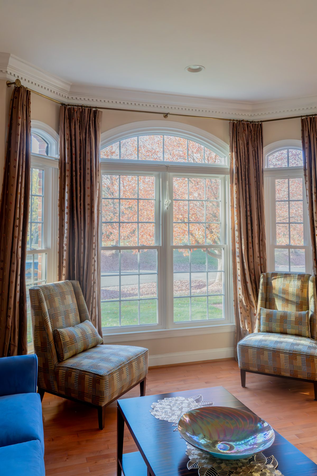 White Vytex Fortis double-hung windows with arched tops and colonial grids in a formal sitting room