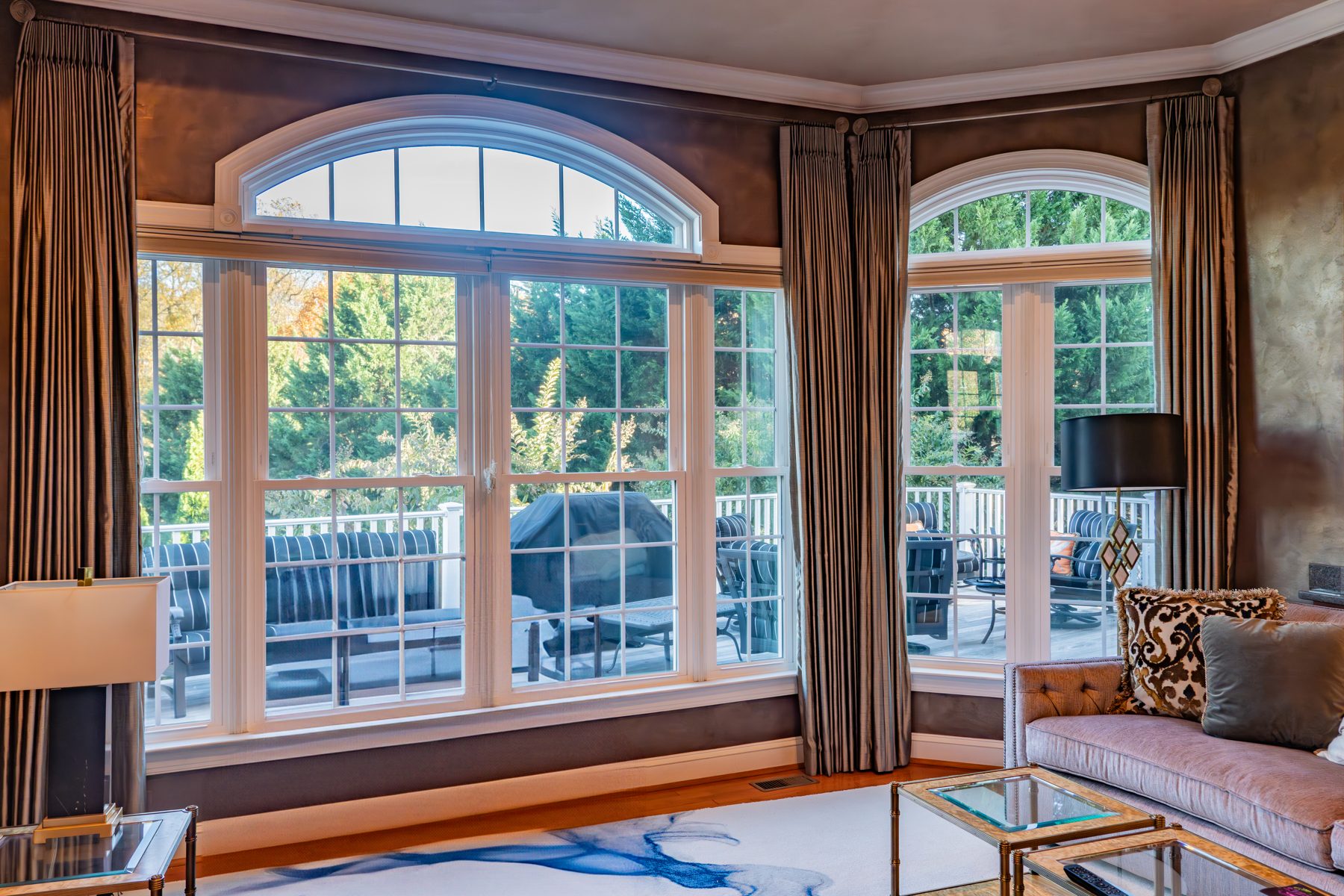 Large bank of white Vytex Fortis double-hung windows with arched transoms and colonial grids in a luxury living room