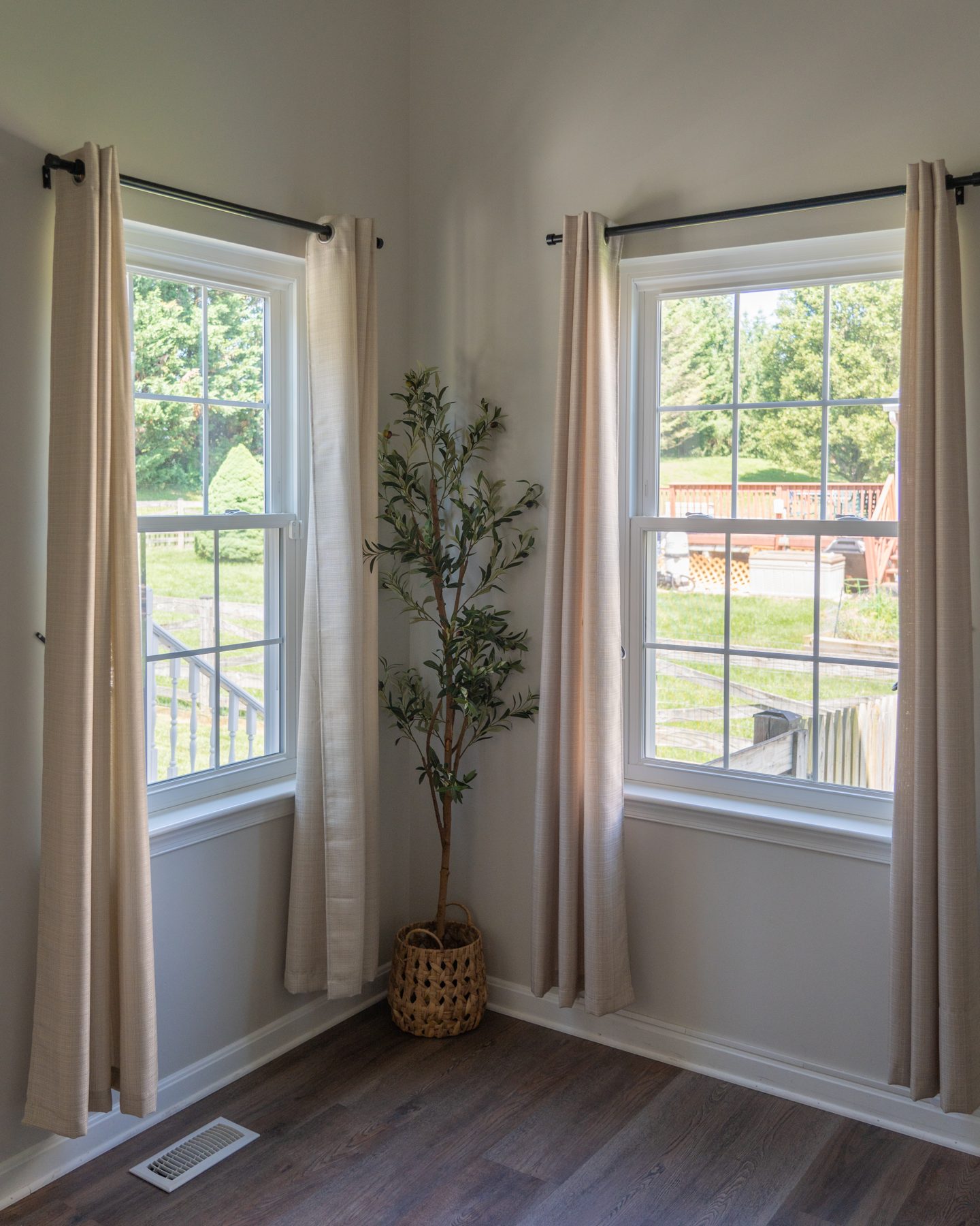 White Vytex Fortis double-hung replacement windows with colonial grids brightening a corner sitting room with hardwood floors