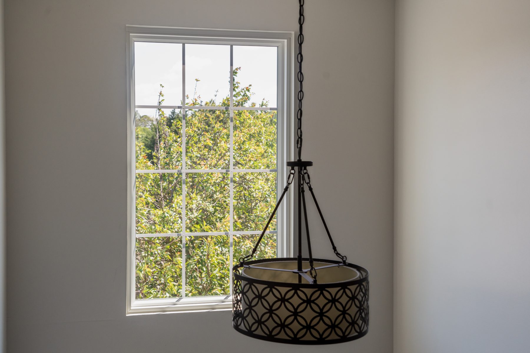 White Vytex Fortis vinyl replacement window with colonial grilles and a decorative pendant light